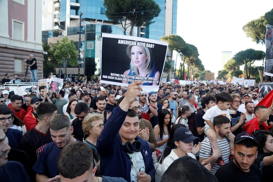 A demonstrator holds a sign with a picture of Ivanka Trump reading "American Nepo Baby – Buying protected areas like shoes and high class dresses in the shopping centre" as protestors gather in front of Albania's Prime Minister's Office in Tirana on June 4, 2026.