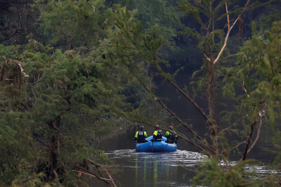 Rescuers paddle an inflatable boat as they search along a waterway following flash flooding in Kerrville, Texas, on July 6, 2025.