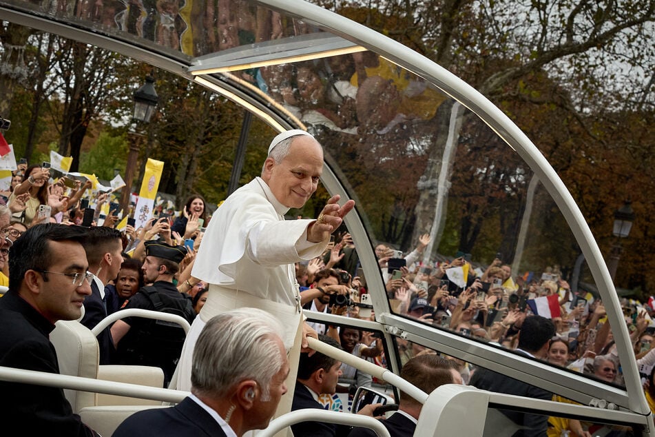 Pope Leo XIV waves to the crowd from the popemobile as he rides down the Champs-Elysees Avenue on September 26, 2026. He held an open-air mass in Paris with hundreds of thousands in attendance.