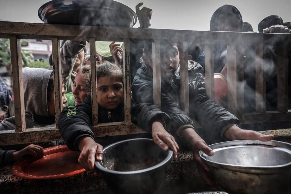 Displaced Palestinian children gather to receive food at a government school in Rafah in the southern Gaza Strip.