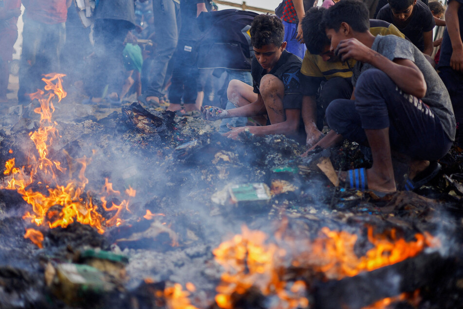 Palestinians search for food among burned debris in the aftermath of an Israeli strike on an area designated for displaced people in Rafah.