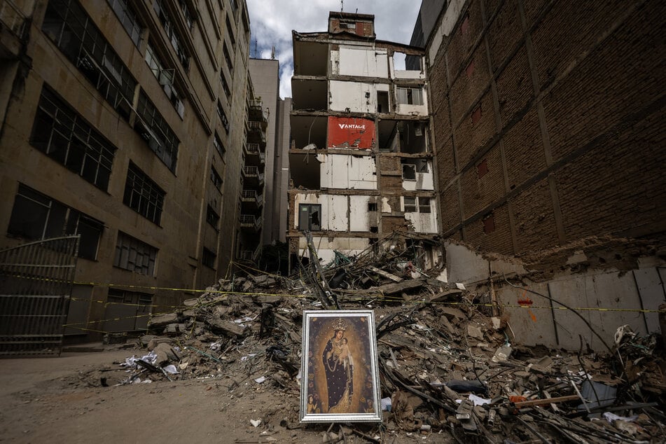 A painting of the Virgen de la Pobreza, patroness of Pereira, is placed by a parishioner in front of the rubble of a building after an earthquake, on August 14, 2026.