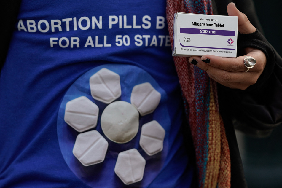 An abortion rights activist holds a box of mifepristone during a rally in front of the US Supreme Court on March 26, 2024.