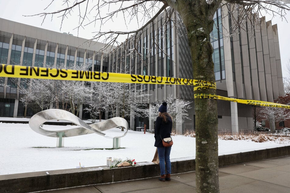A woman pauses next to flowers left outside the Barus & Holley engineering building following a shooting at Brown University, in Providence, Rhode Island, on December 14, 2025.