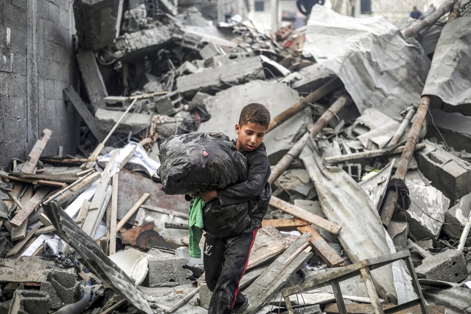 A young Palestinian boy carries a bag through rubble and debris following an Israeli airstrike in Nuseirat in the central Gaza Strip on October 23, 2026.