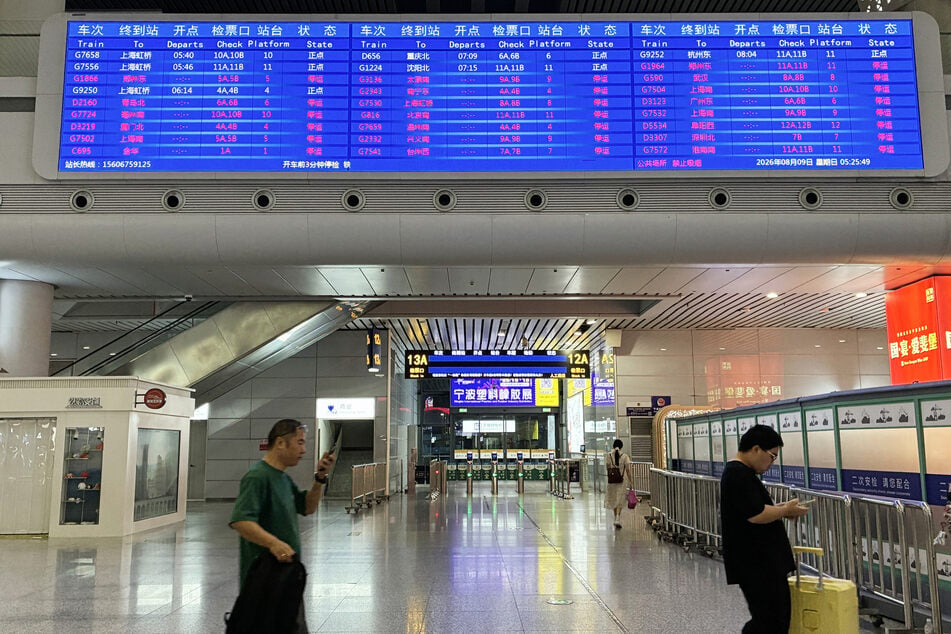Passengers walk beneath a departure board at Ningbo railway station after most trains were canceled due to approaching Typhoon Dolphin on Sunday.