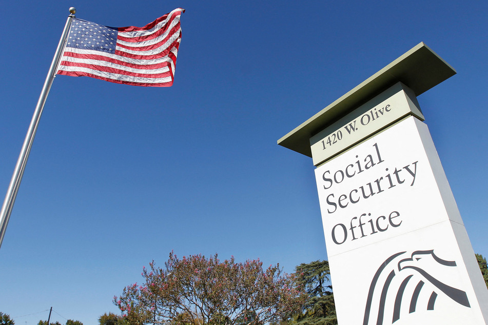 An American flag flutters in the wind next to signage for a US Social Security Administration office in Burbank, California.