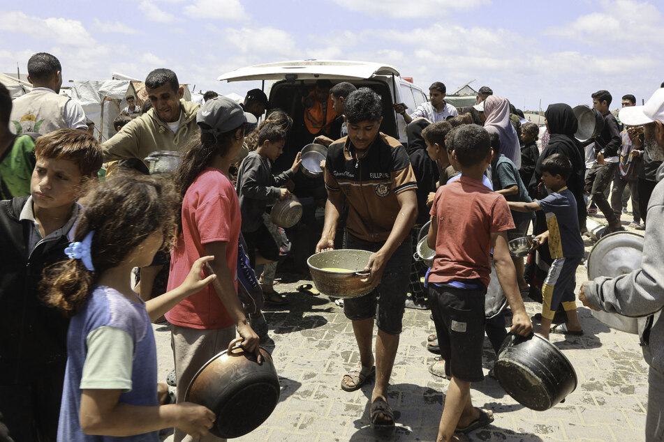 Palestinians, many of them children, gather in front of a hot meal distribution truck at a displacement camp near Gaza City's port on May 22, 2025.