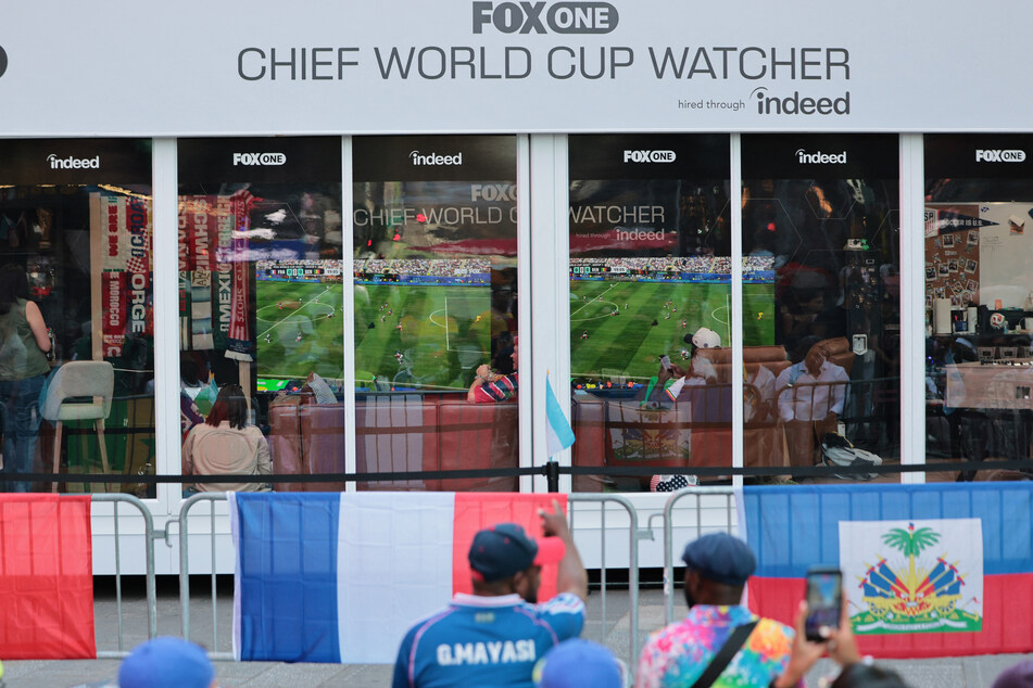 People look on as Austin Franklin and Kevin Akoto, FOX One Chief World Cup Watchers, watch the Senegal versus France World Cup match in Times Square on June 16, 2026.