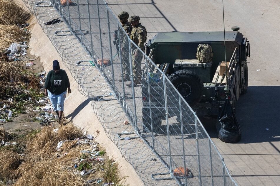An immigrant passes Texas National Guard soldiers at the US-Mexico border on January 9, 2023, in El Paso, Texas.