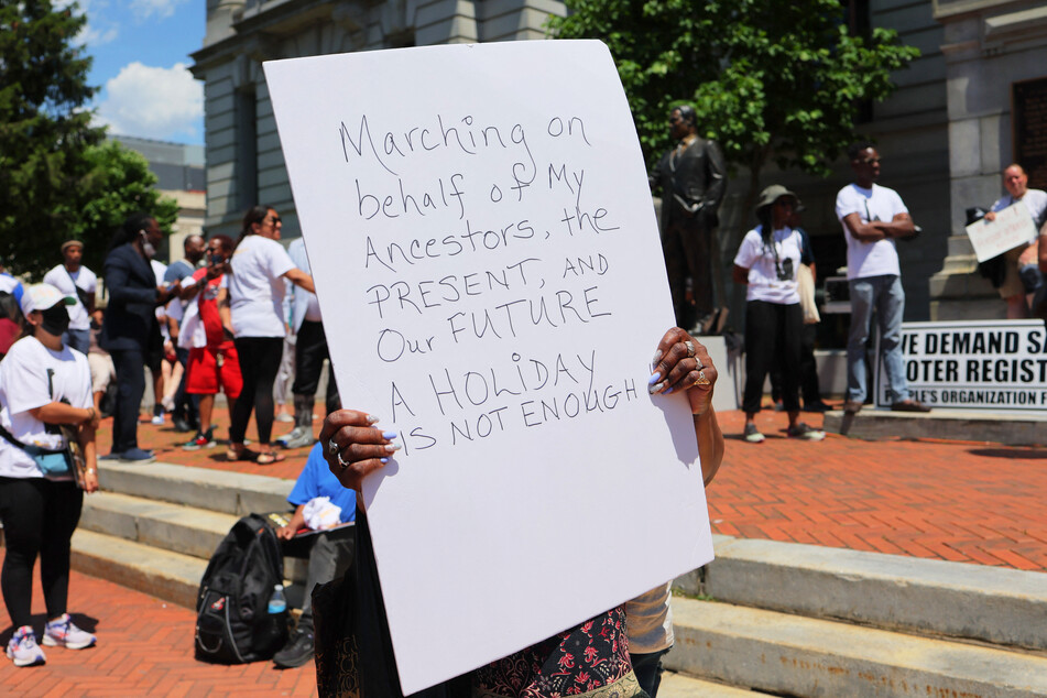 A person holds up a sign during a Juneteenth reparations rally at Newark City Hall on June 17, 2022.