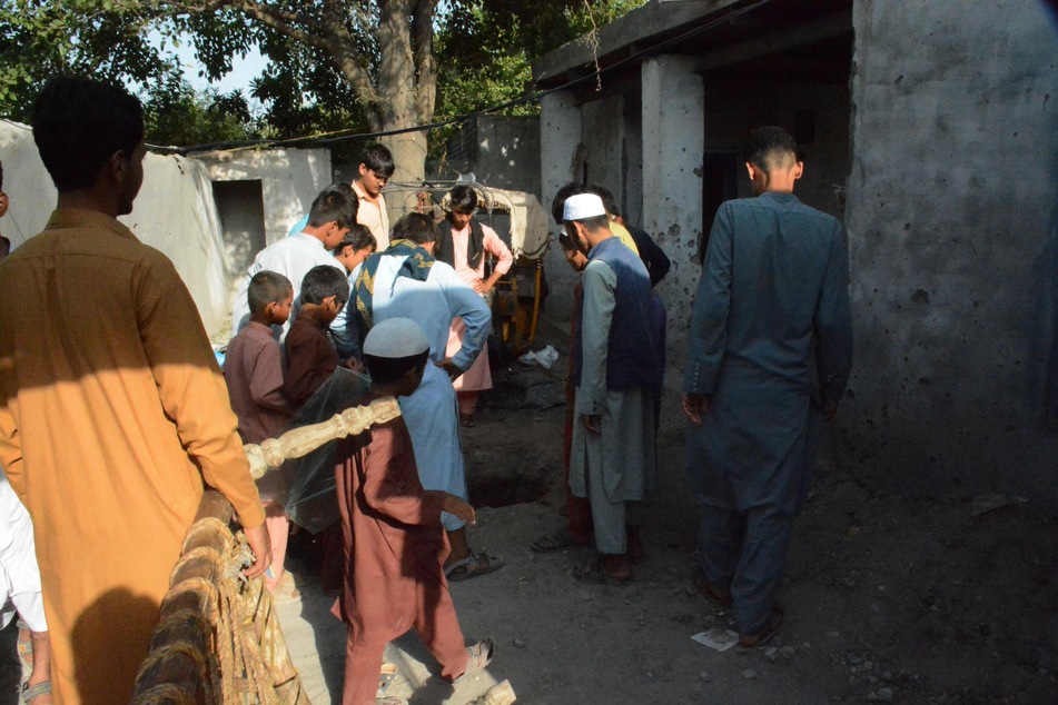 People gather at the site of a US airstrike on a ISIS-K target in Nangarhar Province, Afghanistan.