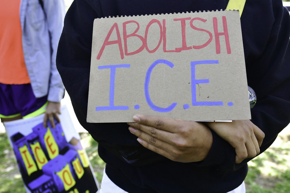 An activist holds a sign reading "Abolish ICE" at a rally in opposition to the detention and deportation of migrants.