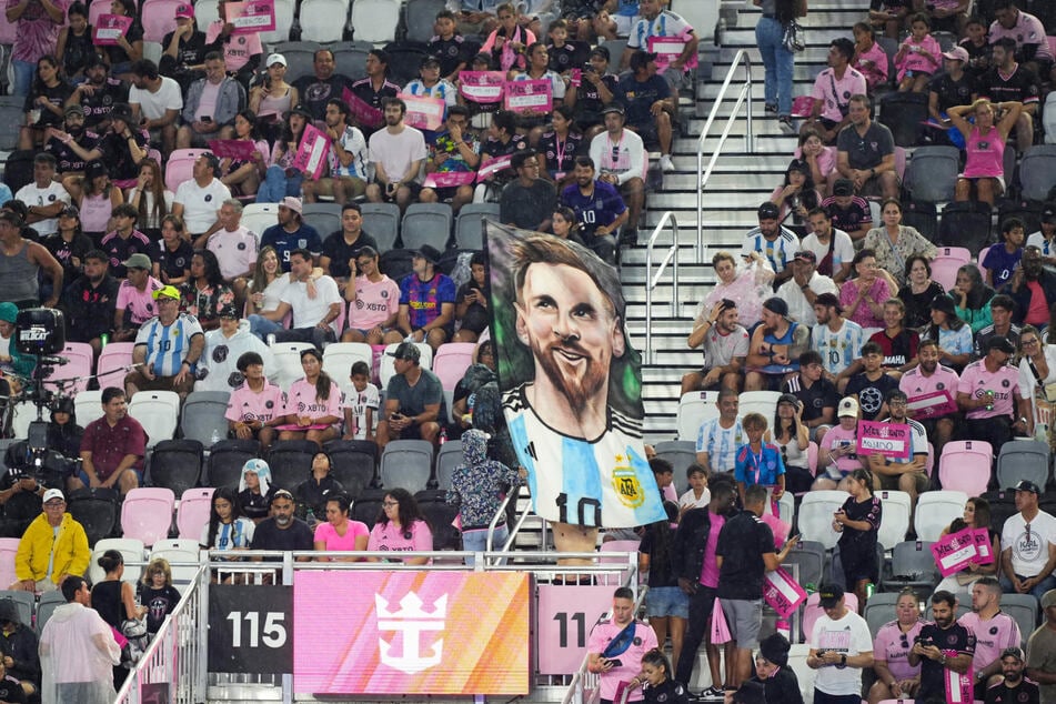 Inter Miami CF fans hold up Lionel Messi signs and banners as he is introduced at The Unveil event and press conference at DRV PNK Stadium.