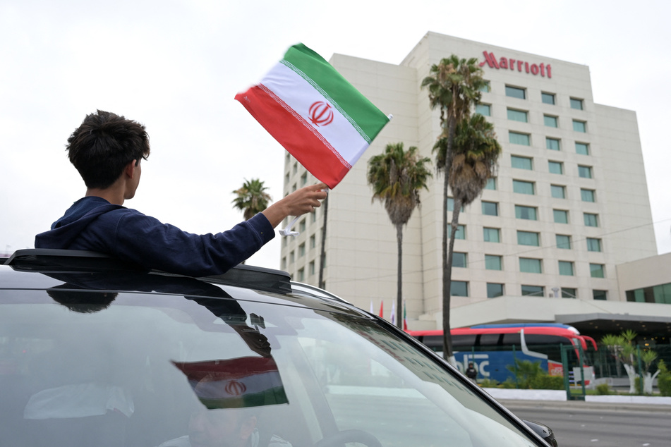A person waves an Iranian flag from a vehicle outside the hotel where Iran's World Cup players are staying following their arrival in Tijuana, Mexico, on June 7, 2026.