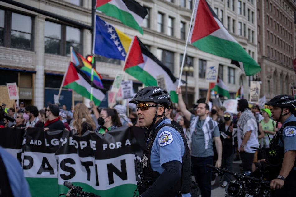 Police officers stand near marching activists as they wave Palestinian flags ahead of the Democratic National Convention in Chicago, Illinois.