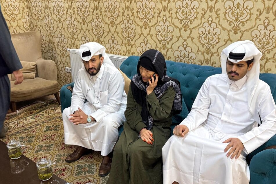 An image obtained from a diplomatic source in Kabul shows released US citizen Faye Hall (c.) – flanked by Chargé d'affaires of the Qatar Embassy in Afghanistan, Mirdef Alqashouti (l.) – speaking on the phone after being released by the Taliban on Saturday.