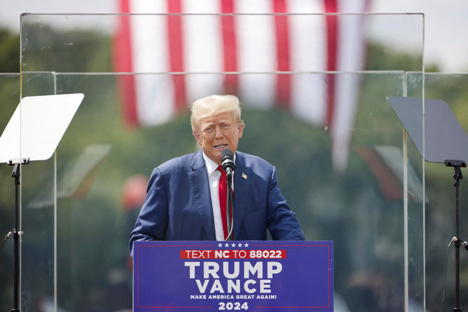 Republican presidential nominee Donald Trump speaks from behind bulletproof glass during a campaign rally at the North Carolina Aviation Museum & Hall of Fame in Asheboro.