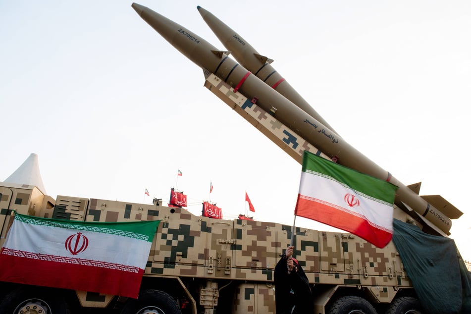 Iranian flags hang from a camouflaged transporter carrying Zolfaghar and Qadr missiles at Azadi Square in Tehran, Iran. New images have revealed that Tehran's strikes on US military bases caused heavier damage than previously reported, as hostilities continue.