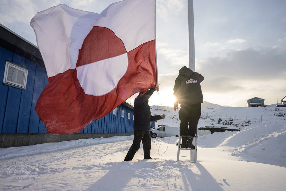 Men hoist a Greenlandic flag in the capital city of Nuuk on March 24, 2026.