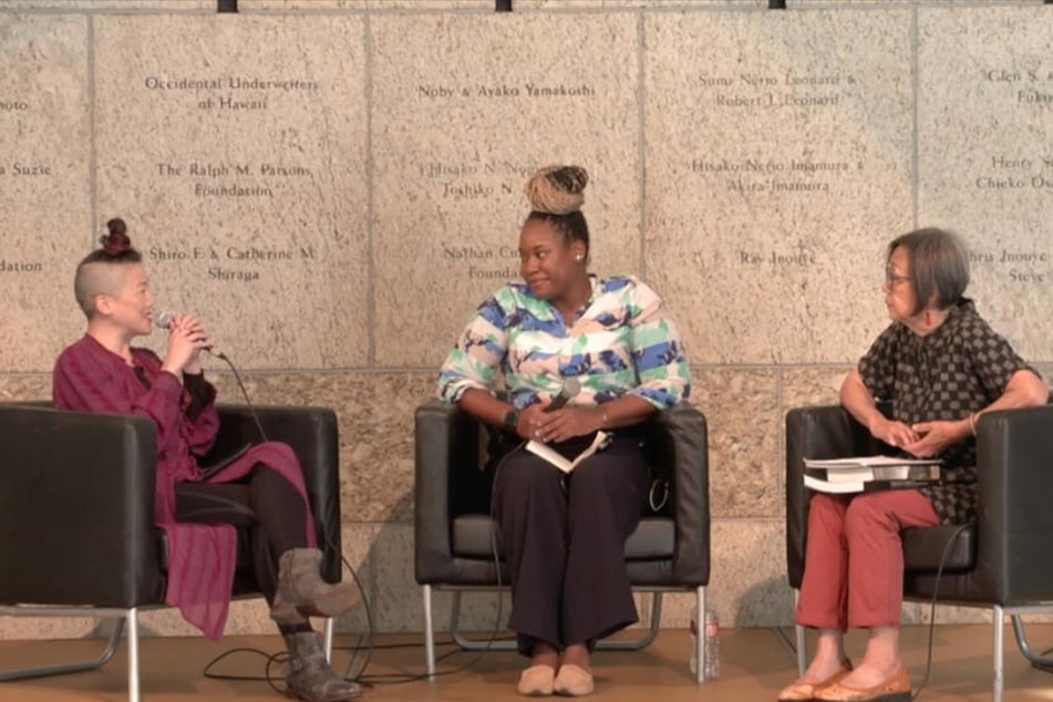 traci kato-kiriyama (l.) and Kathy Masaoka (r.) of the National Nikkei Reparations Coalition speak with Dreisen Heath of Human Rights Watch at the Japanese American National Museum in Los Angeles on the 80th anniversary of Executive Order 9066.