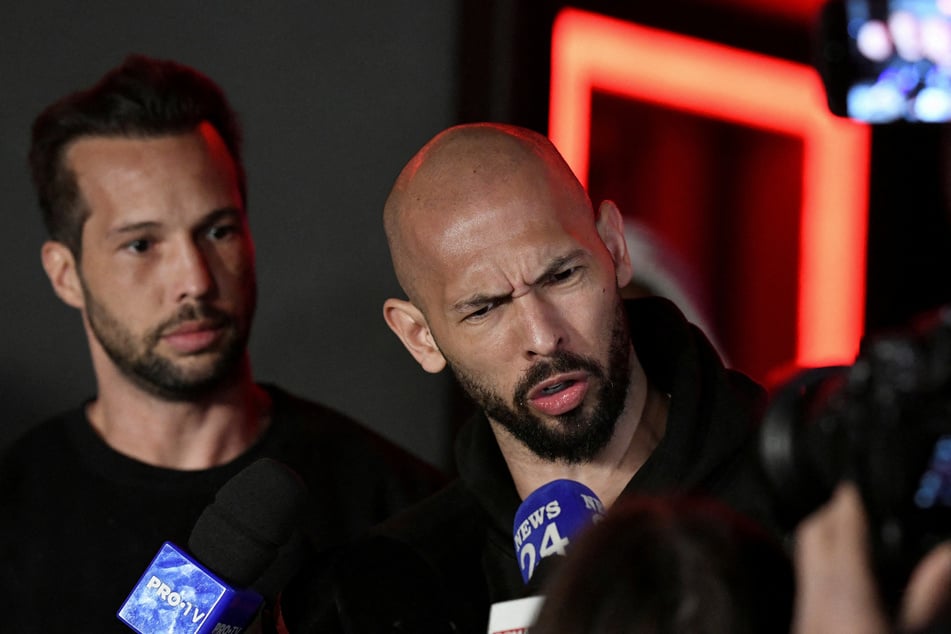 Tristan Tate (l.) and Andrew Tate (r.) deliver a press statement in front of their house after landing back in Romania on March 22, 2025. British prosecutors have filed a request for the brothers' extradition from the US to face rape and sex trafficking charges in the UK.