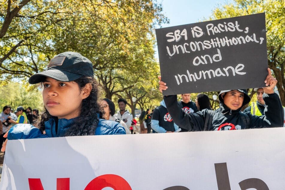 A protester raises a sign reading "SB 4 is racist, unconstitutional, and inhumane" during a rally against the legislation in Austin, Texas.