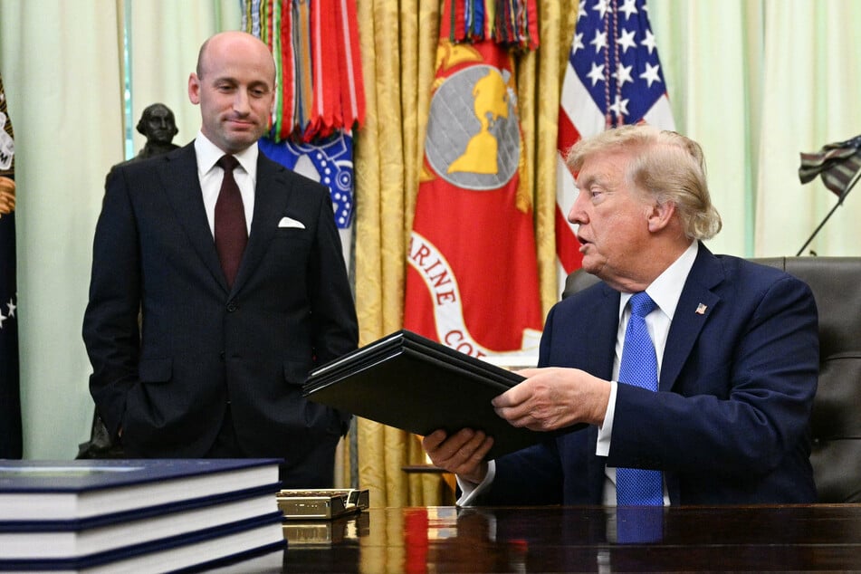 White House Deputy Chief of Staff Stephen Miller (L) smiles as President Donald Trump (R) holds signed executive orders in the Oval Office of the White House in Washington, DC, on Thursday.