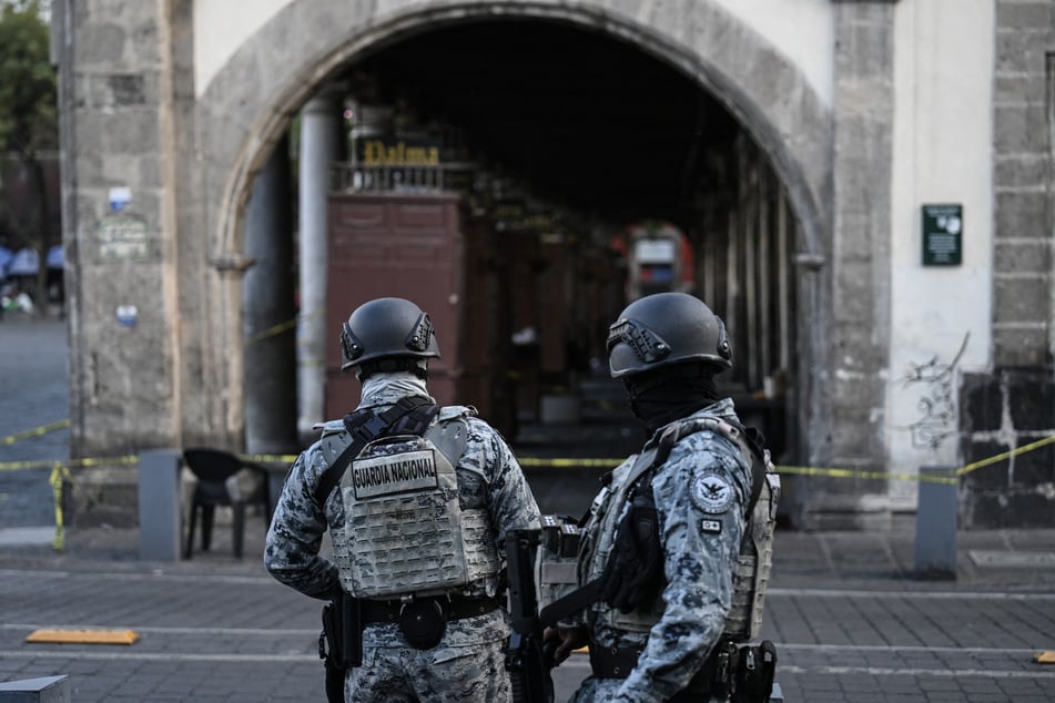 Two Mexican National Guard troops stand guard at a crime scene where one was killed and two were wounded during a shooting in Mexico City's historic center.