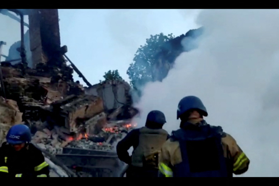 Emergency crew members tend to a fire after a school building was shelled in the village of Bilohorivka.