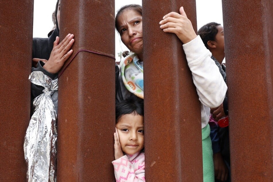An Ecuadoran mother and her 4-year-old daughter await volunteer assistance while stuck in a makeshift camp between border walls between the US and Mexico.