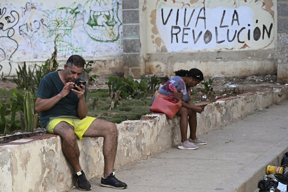 People look at their phones on a street during a blackout in Havana, Cuba, on August 1, 2026.