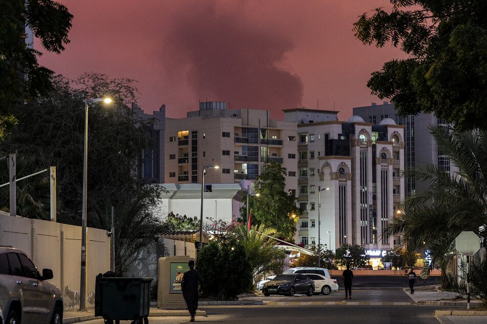 Bystanders watch as a plume of black smoke rises from the port of Fujairah in the UAE on March 4, 2026.