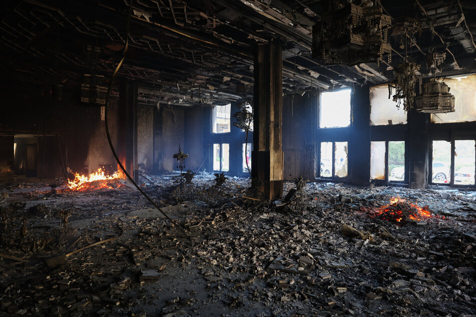 A man looks inside as a fire burns in a room of the Tishrin residential palace of Syria's ousted president Bashar al-Assad in Damascus' al-Muhajirin area on Sunday after Islamist-led rebels took the Syrian capital in a lightning offensive that ended five decades of Baath rule in Syria.