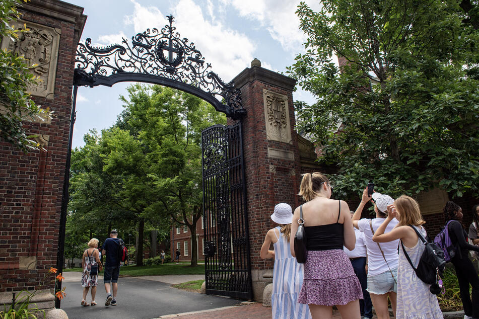 People take photos by the entrance to Harvard Yard in Cambridge, Massachusetts, on June 29, 2023.