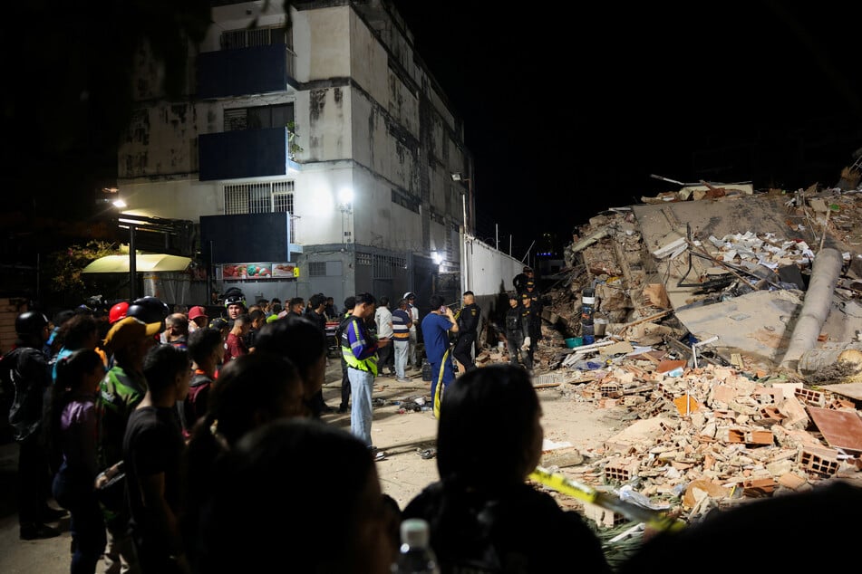 People gather as emergency services work at the site of a collapsed building in Caracas on June 25, 2026, after earthquakes hit Venezuela.
