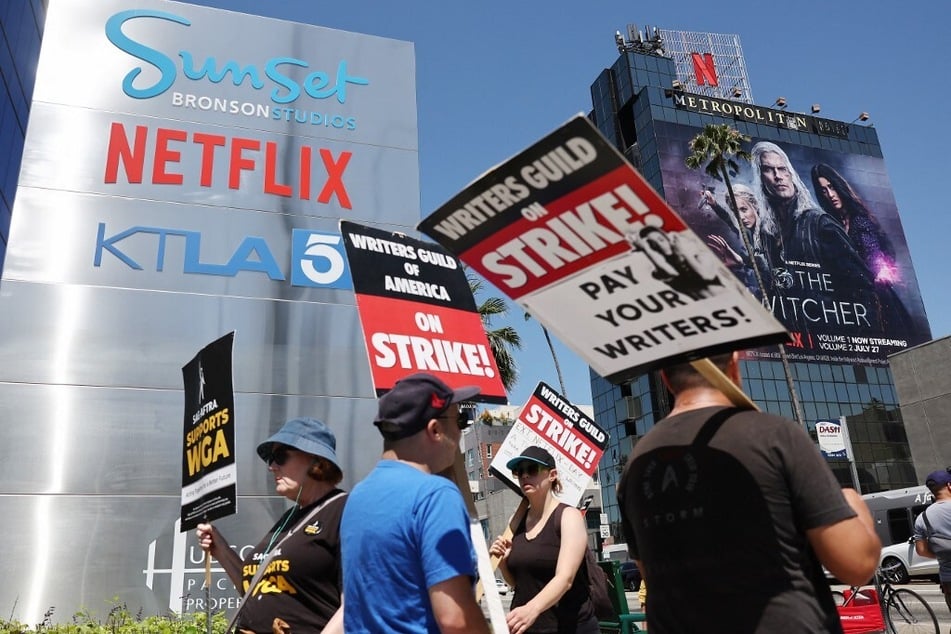 People carry signs as SAG-AFTRA members walk the picket line in solidarity with striking WGA workers outside Netflix offices on July 11, 2023, in Los Angeles, California.