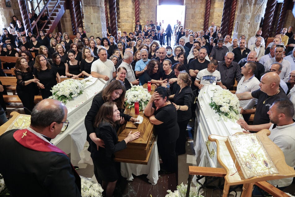 Relatives of a man who was killed along with his son and daughter in an Israeli strike that targeted their car earlier this week in southern Lebanon mourn over their coffins during their funeral in the border village of Qlayaa on June 3, 2026.
