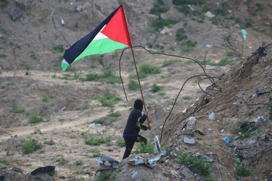 A Palestinian youth waves the flag of Palestine in Khan Younis in the southern Gaza on February 20, 2025.