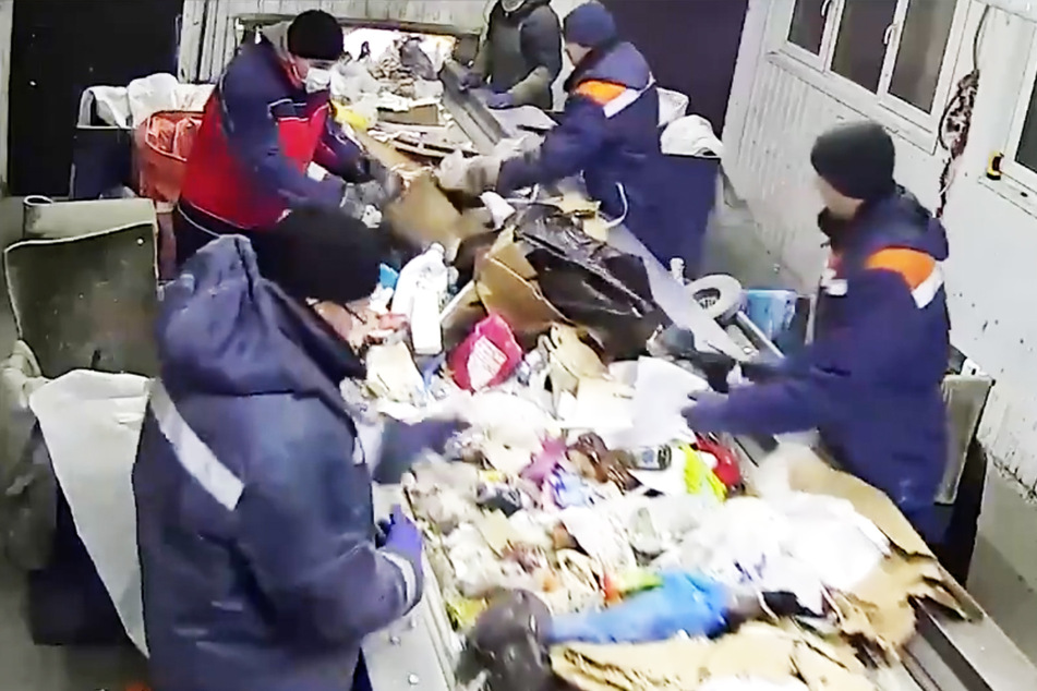 The cat rescuer (2nd from right) discovers the knotted garbage bag on the conveyor belt.
