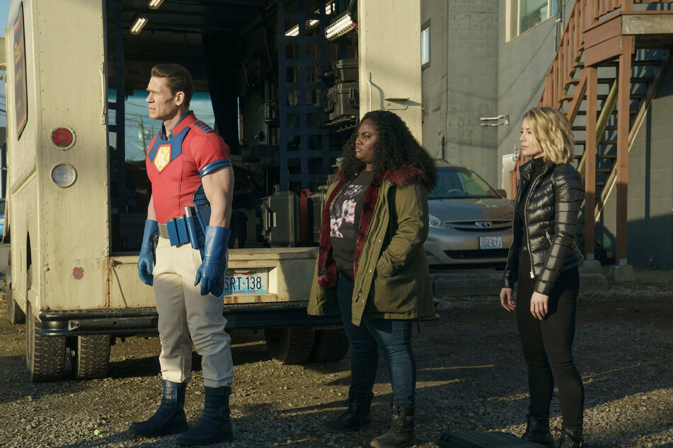 In the series' fifth episode, Peacemaker (l) bonds with his teammates, including Adebayo (m) and Harcourt (r), after successfully destroying a lab that contained butterflies and honey.