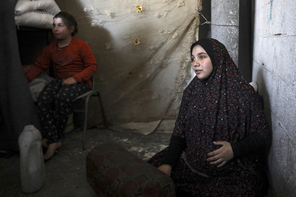 A pregnant Palestinian woman displaced from northern Gaza sits in a warehouse where she is taking shelter in Rafah, in the southern Gaza Strip, on February 29, 2024.