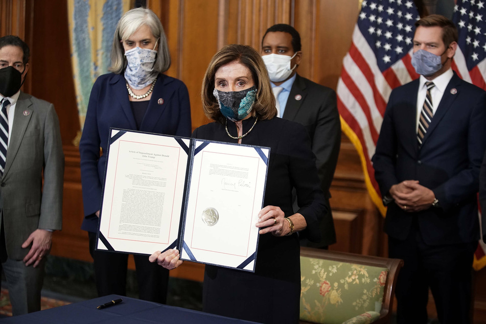 House Speaker Nancy Pelosi holding up the article of impeachment that passed with bipartisan support in Wednesday's vote.