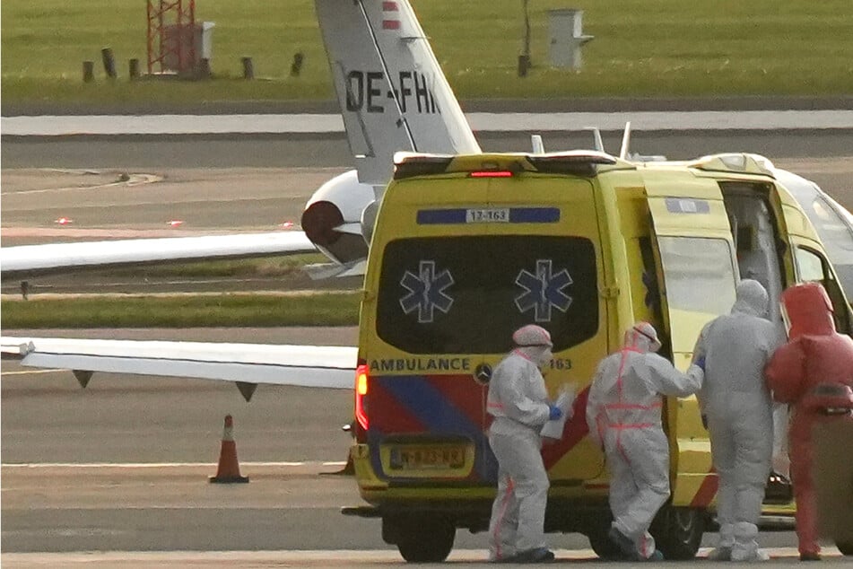 A person in a hazmat suit is escorted to a ambulance from a medical aircraft allegedly carrying some of the passengers from the cruise ship.
