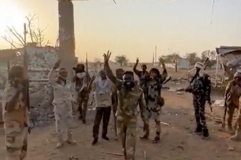 Members of Sudan's paramilitary Rapid Support Forces stand in front of the main gate of the 22nd SAF Infantry Division, in Babanusa on December 1, 2025.