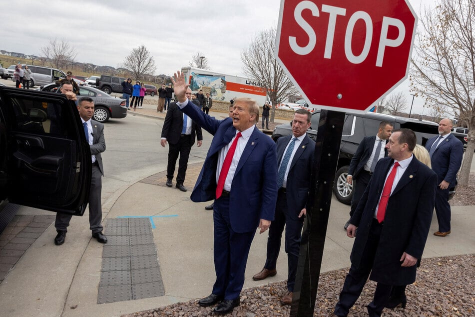 Donald Trump (c.) will stay on Maine's presidential primary ballot after the state's top court said the US Supreme Court must settle the issue of his eligibiity.