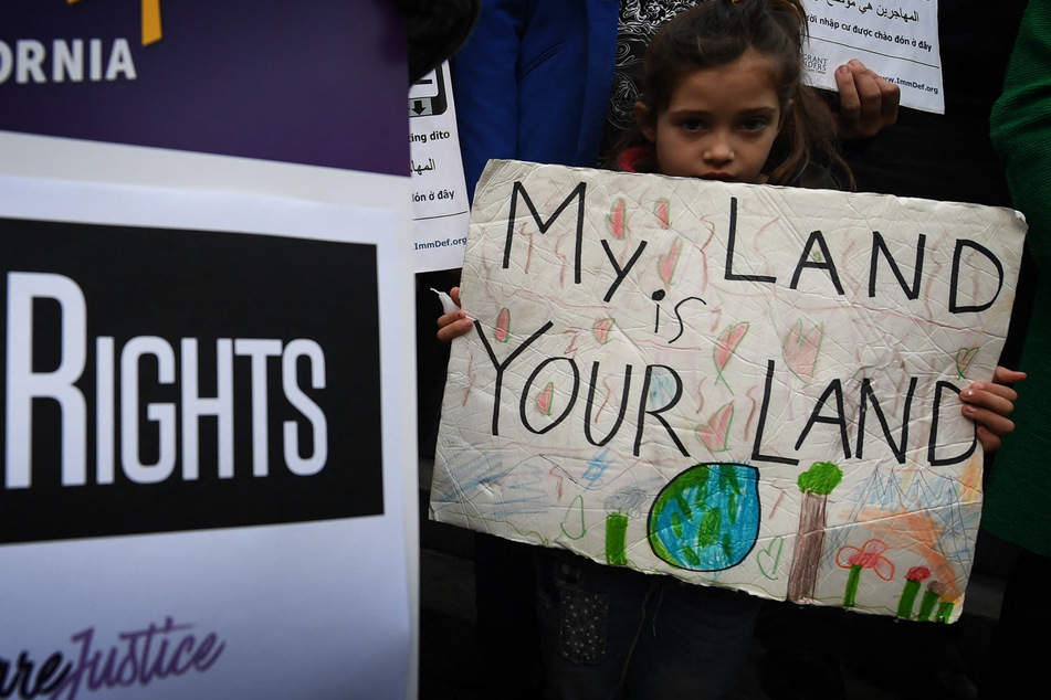 Maya Casillas (7) joins a migrant rights group during a vigil to protest against US President Donald Trump's crackdown on "sanctuary cities" outside the City Hall in Los Angeles on January 25, 2017.