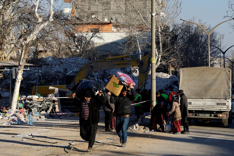 People carrying belongings walk in the aftermath of a deadly earthquake in Kahramanmaras, Turkey.